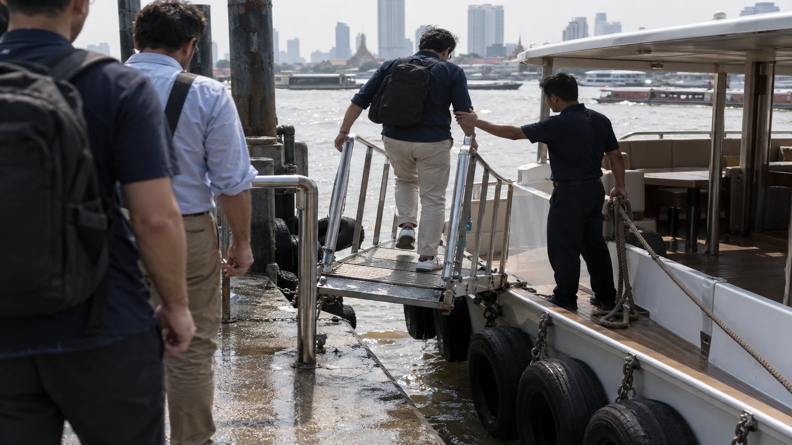 Men boarding a private charter boat from a Bangkok river pier in the afternoon