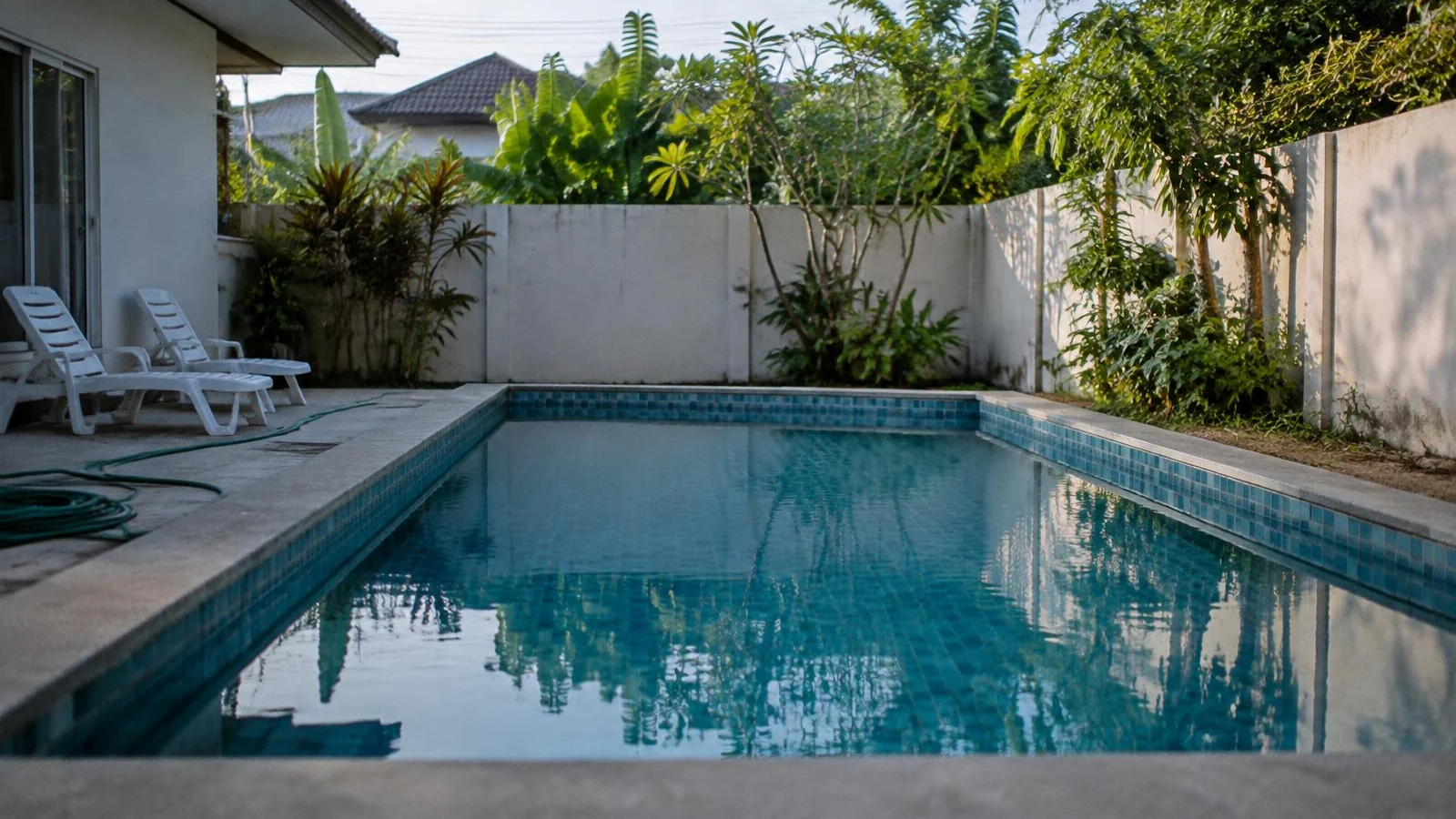 An empty private pool at a walled villa on the outskirts of Bangkok in the morning