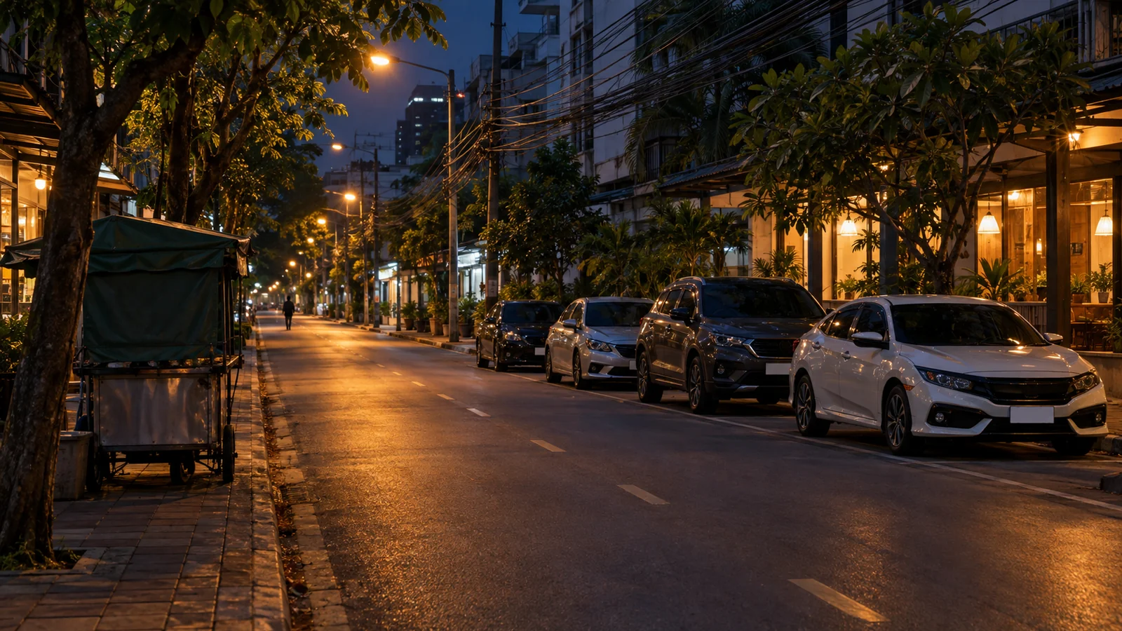 A Bangkok nightlife street on a weeknight with venues lit and taxis waiting at the kerb