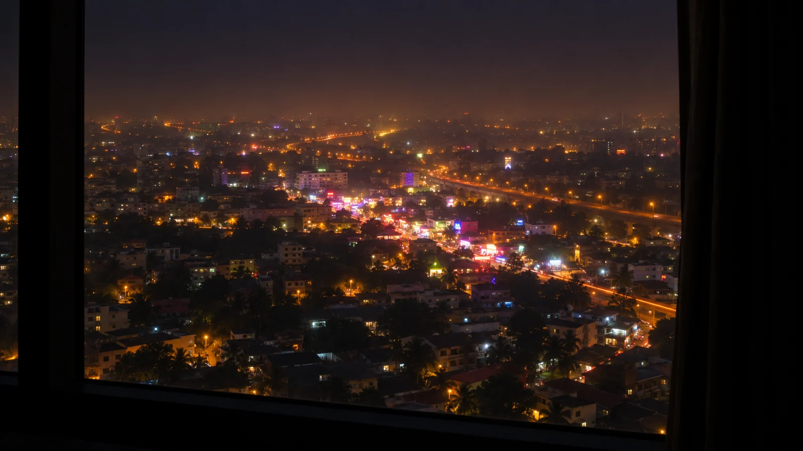 A high floor hotel window looking out over the Bangkok skyline at night