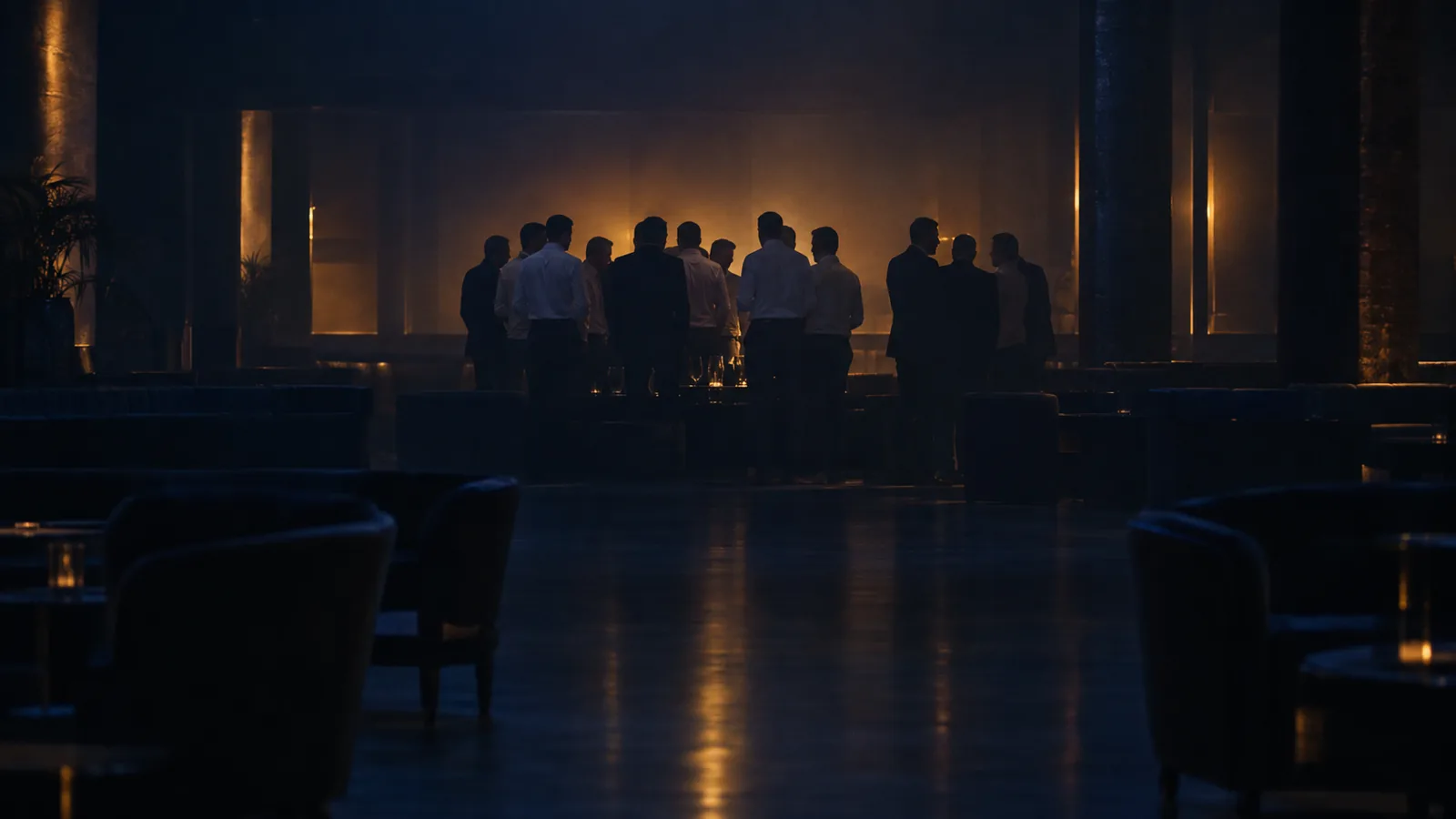 A large group of men standing together in silhouette across a dark room