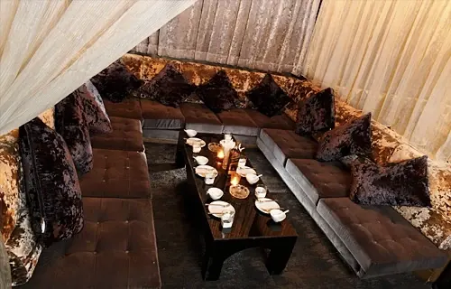 A large curtained VIP sofa set with a low table and candles