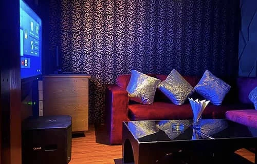 A small private room with a sofa, a table and a screen